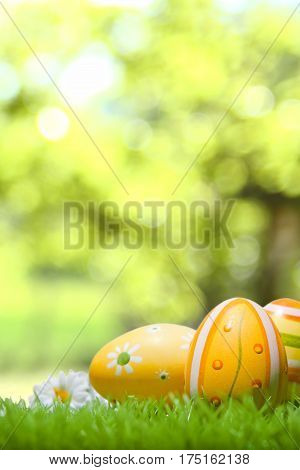 Spring decoration with Easter eggs and flowers on a green meadow, bokeh in the background