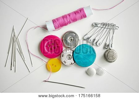 needlework and tailoring concept - sewing buttons, needles, pins and thread spool