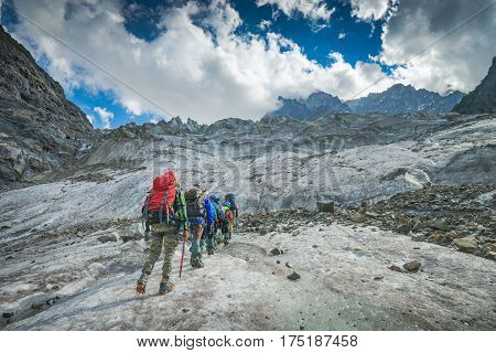 Group of hikers with backpacks climb the glacier to the peak of mountain. Caucasian mountains Georgia Svaneti region.