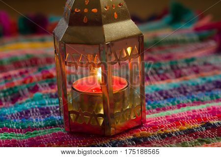 pink candle on a colorful handmade fabric .