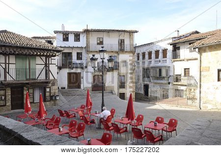 CANDELARIO, SPAIN - AUGUST 11, 2016: Man sitting in an outdoors bar in a plaza of Candelario a typical mountain village in the province of Salamanca Spain.