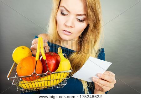 Worried Woman Holding Shopping Basket With Fruits