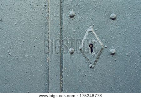 Rusty keyhole on gray metal door. Mortise lock on rivets in an old steel door painted with gray paint