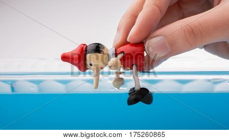 Hand Holding Pinocchio On In  Water