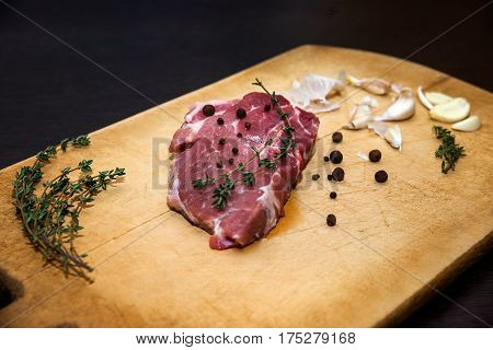 Beef steak. Raw marble beef on a cutting board. On a black background for text design or restaurant menus. Food background. Horizontal photo.