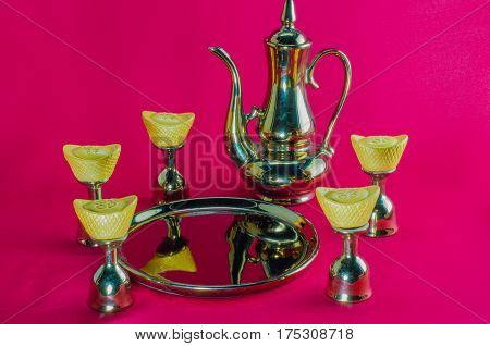 Gold ingot Gold jug Tea glass golden plates on red background.