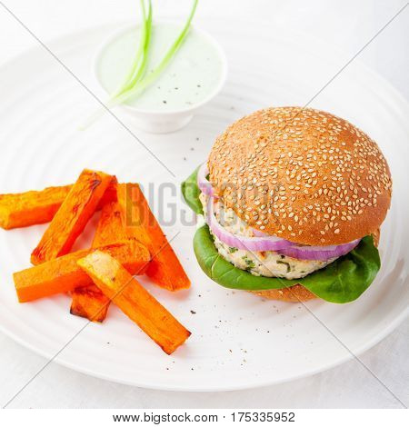 Chichen burger spinach onion and roasted sweet potato batat on a white plate.
