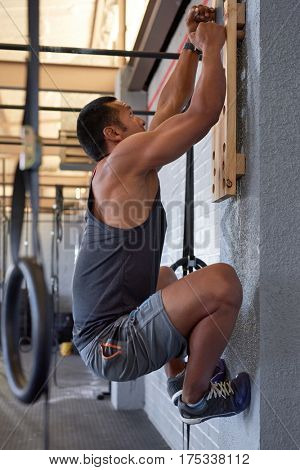 Musuclar man doing intense workout training with pegboard crossfit exercise for strength