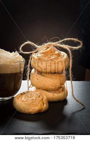 Homemade cookies from cottage cheese and meringue tied up twine with cup of coffee on black slate dish.