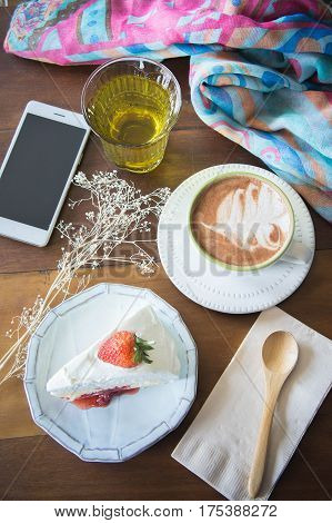 coffee cup and delicious cake strawberry and relax time moblie on table in coffee shop