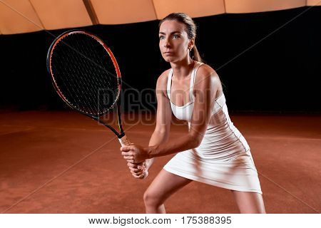 Sportswoman at the tennis court with racquet. Indoor tennis court
