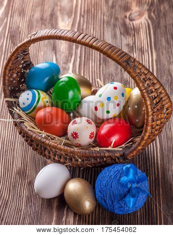 Colorful easter edds in basket on a brown wooden table