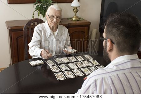 Grandma puts tarot grandson. 
Age fairy puts tarot cards 
Very old woman puts a man tarot cards. 
Fortune-telling with tarot cards.