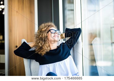 Business woman relaxing working at office desk laid back resting on chair with hands behind head