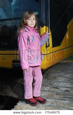 Bambina in abiti rosa permanente su trattore cingolato giallo nel buio