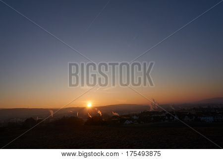 sunset with smoke and condensation trails on a business day