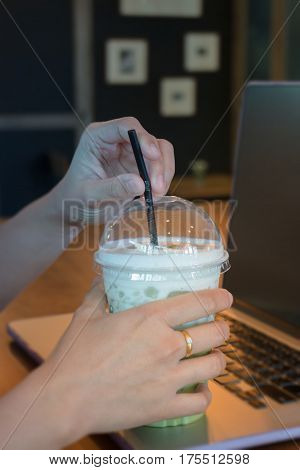 Woman Hand On Iced Milk Green Tea During Typing stock photo