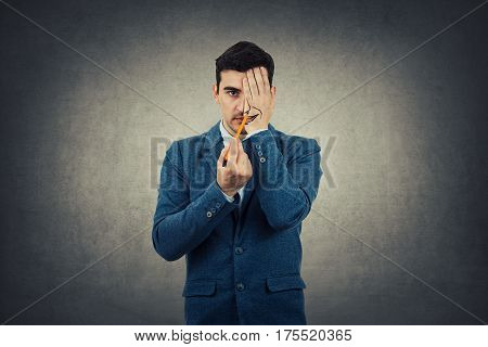Portrait of a businessman hiding half face with his hand trying to draw a big smile. Create new identity grey wall background.