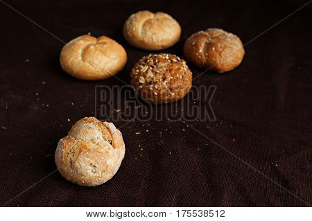 variety of small breads with seeds on black background