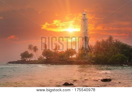 White lighthouse Dondra and tropical palm trees against the background of a fantastic sunset Sri Lanka island near Matara.