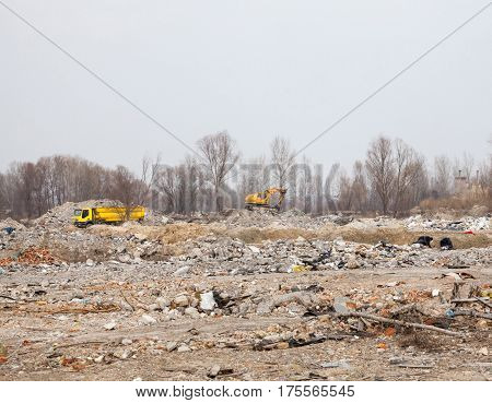 City landfill. Truck and excavator working at a distance.