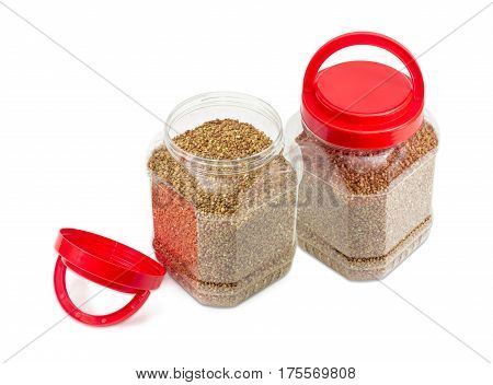 Buckwheat groats peeled from the husk in two transparent plastic containers with the red covers one of them open on a light background