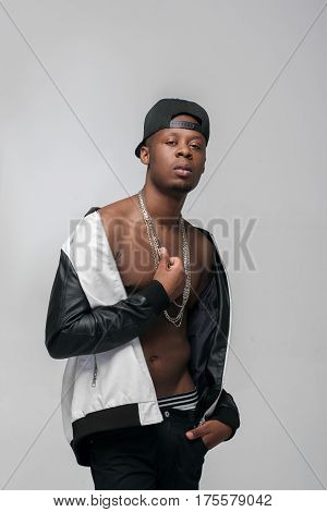 Young african american gangster guy. Problem of substance abuse, crime, social issues, drugs. Ghetto, challenge to society, cheeky, cool, rebellious. Grey background with free space