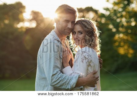 Portrait of an affectionate young couple embracing while enjoying a romantic sunny summer afternoon together in a park