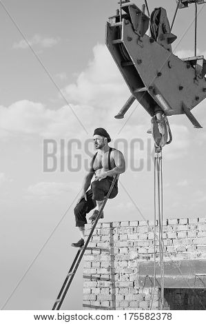 Strong and masculine. Vertical monochrome shot of a retro builder resting on a ladder at construction area building business profession athletic strong crane relax calm thinking black and white