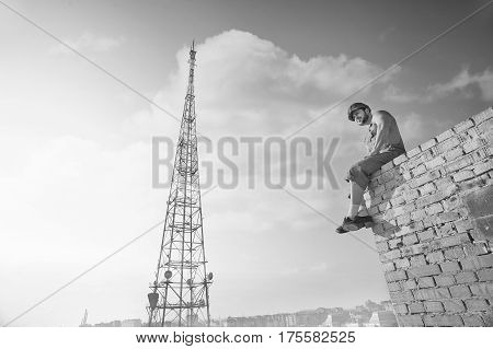 Brick wall. Monochrome low angle shot of a relaxed muscular shirtless builder sitting resting on top of brick wall observing the city copyspace sky summer relaxation rest masculinity fearless concept