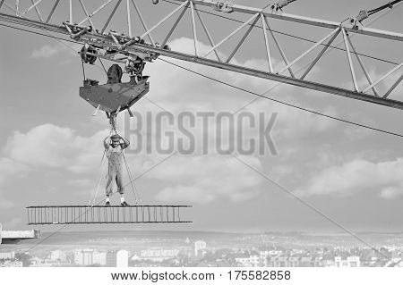 Muscular shirtless retro stressed and devastated builder standing on a crossbar hanging from construction crane above the city looking down with his hand to his head. copy space. failure concept.