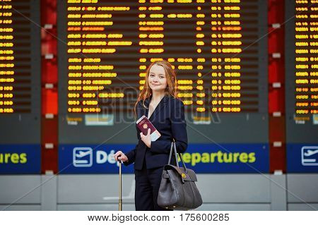 Woman With Hand Luggage In International Airport Terminal, Looking At Information Board