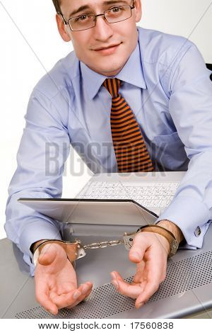 Bonito jovem empresário ligado ao laptop com algemas