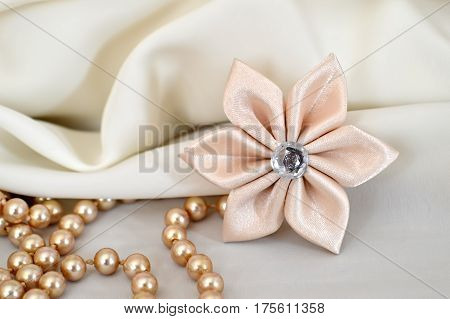 Handmade silk kanzashi flower and pearls on fabric background