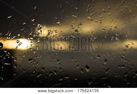 Drops of rain on a window in the sunset