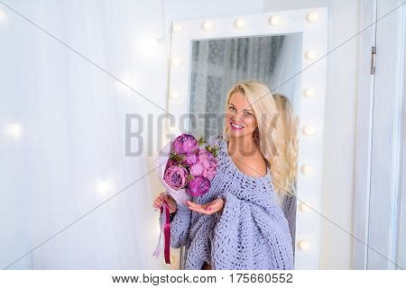 Amazing blonde holds a bouquet of peonies in her hands