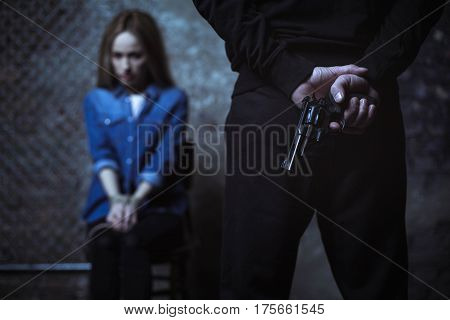 Let us have a conversation. Defenseless captured blonde lady sitting in a dark room being captured by a stranger who holding a gun