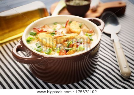 Delicious beer cheese soup with croutons and fried bacon on table