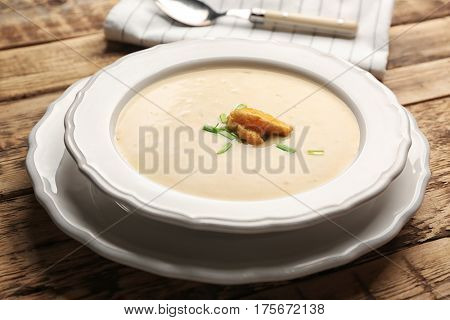 Delicious beer cheese soup with croutons on table