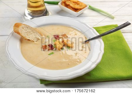 Delicious beer cheese soup with croutons and fried bacon on table