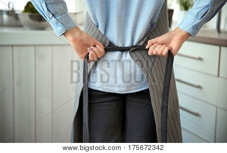 Woman tying up her apron around the waist in kitchen