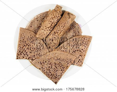 Traditional Ethiopian flatbread from fermented teff flour on a white plate cut and rolled up