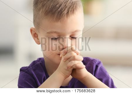 Cute little boy praying at home