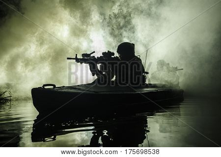 Backlit silhouette of special forces marine operators in military kayak on fire explosion background. Battle operation, bombs exploding