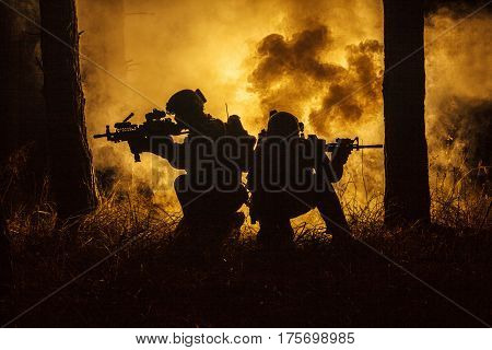 Backlit silhouette of special forces marine operators in forest on fire explosion background. Battle, bombs exploding, they fighting no matter what