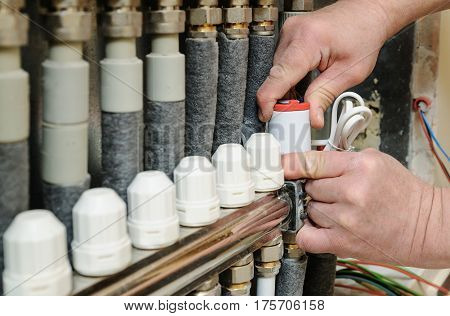 Installation of home heating. Men's hands attaches the servo valve drive underfloor heating.