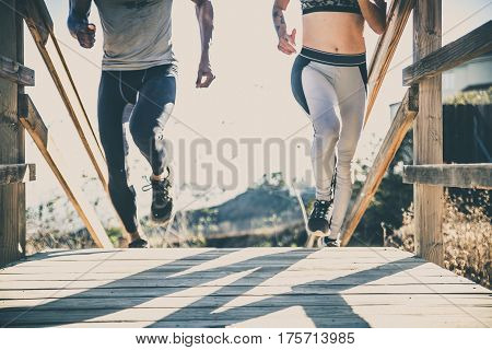 Couple running outdoors, closeup on lower body