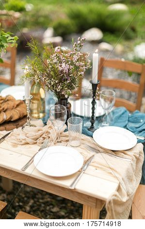 spring festive lunch an outdoors, wedding decor of a table, table layout, the fresh cut bread, bouquet of wild flowers.