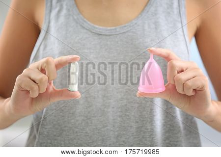 Close up view of woman making choice between menstrual cup and tampon. Gynecology concept