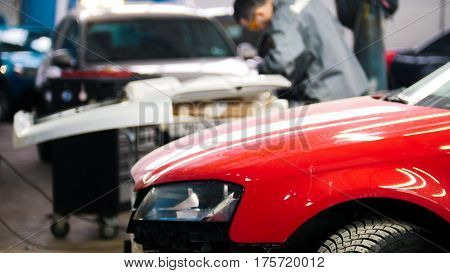 Defocused background - professional car service - man work tinsmith works with a hammer - repairing automobile, telephoto